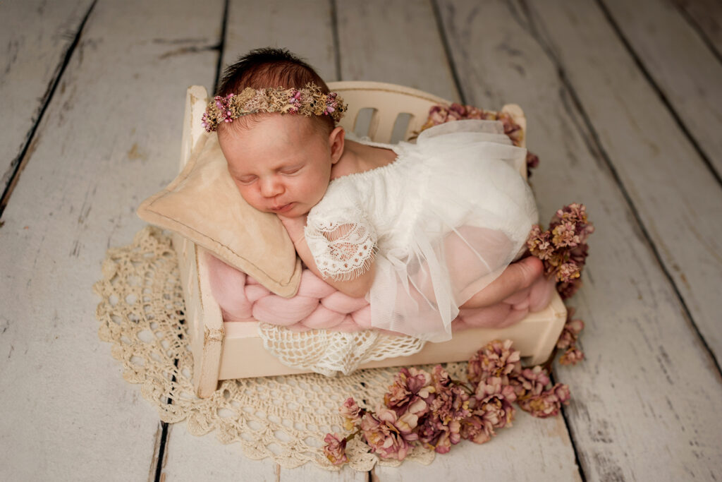 noworodek w wianuszku na sesji pozowanej noworodkowej w studio w kłodzku w kwiatowej aranżacji